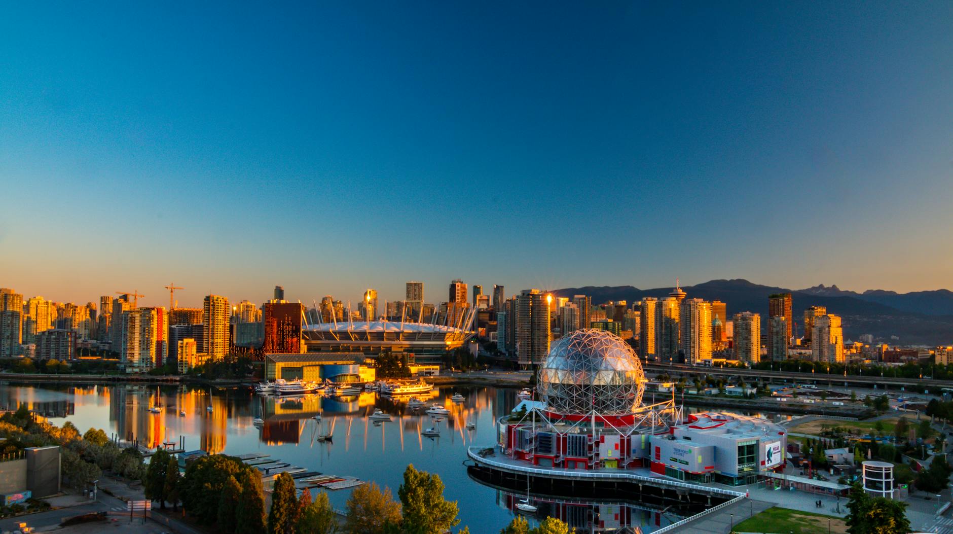 Zachód słońca nad panoramą Vancouver z kopułą Science World odbijającą się w wod