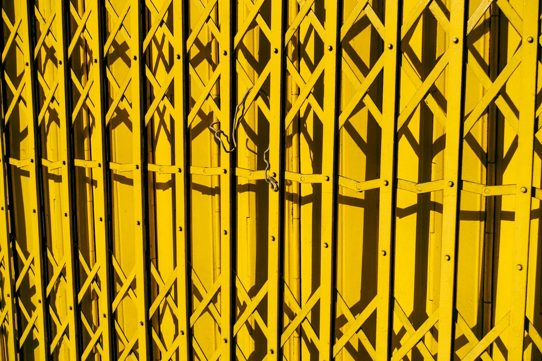 Żółta metalowa brama z geometrycznym wzorem w ostrym słońcu