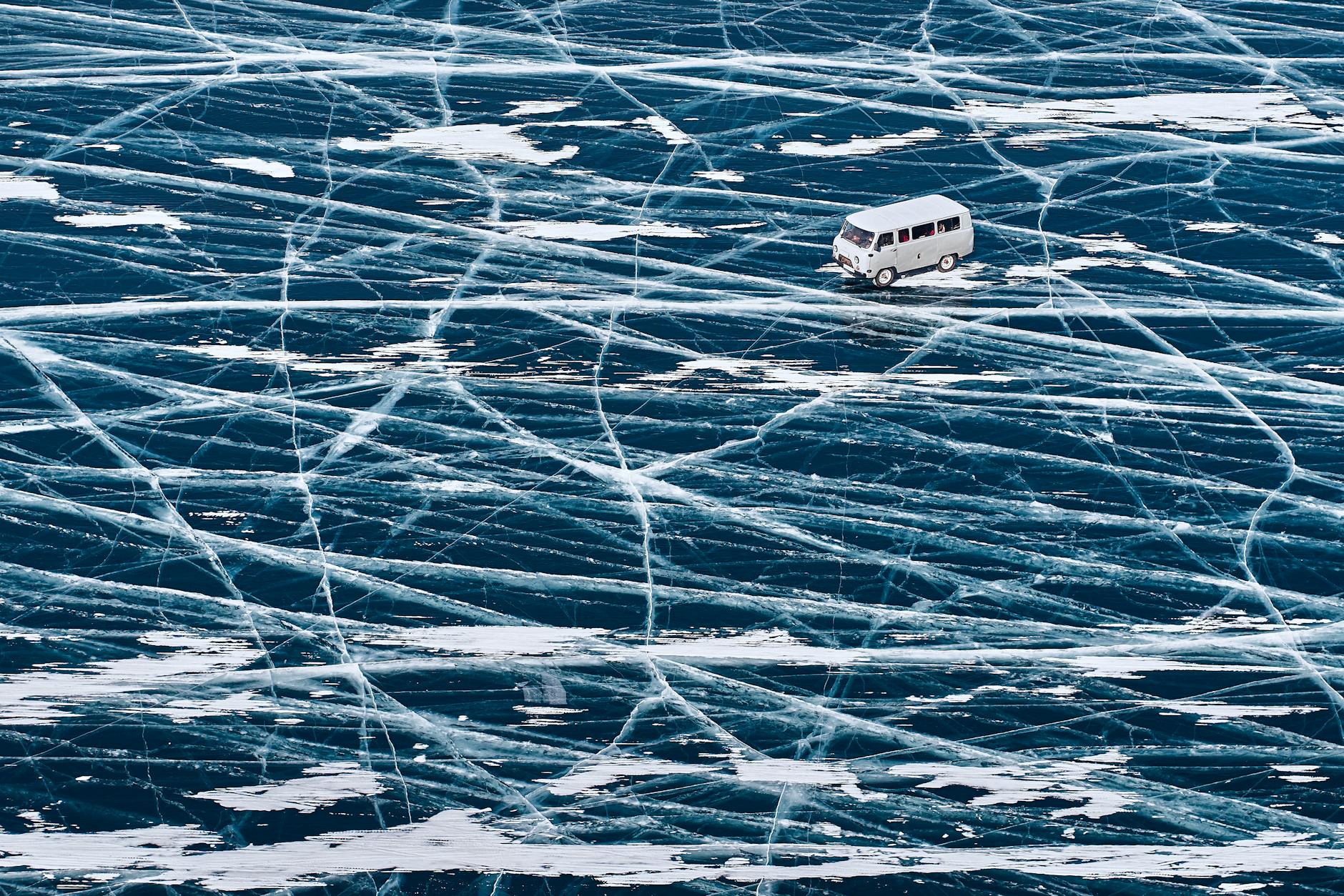 Bus jedzie po zamarzniętej tafli jeziora Bajkał z widocznymi wzorami lodu