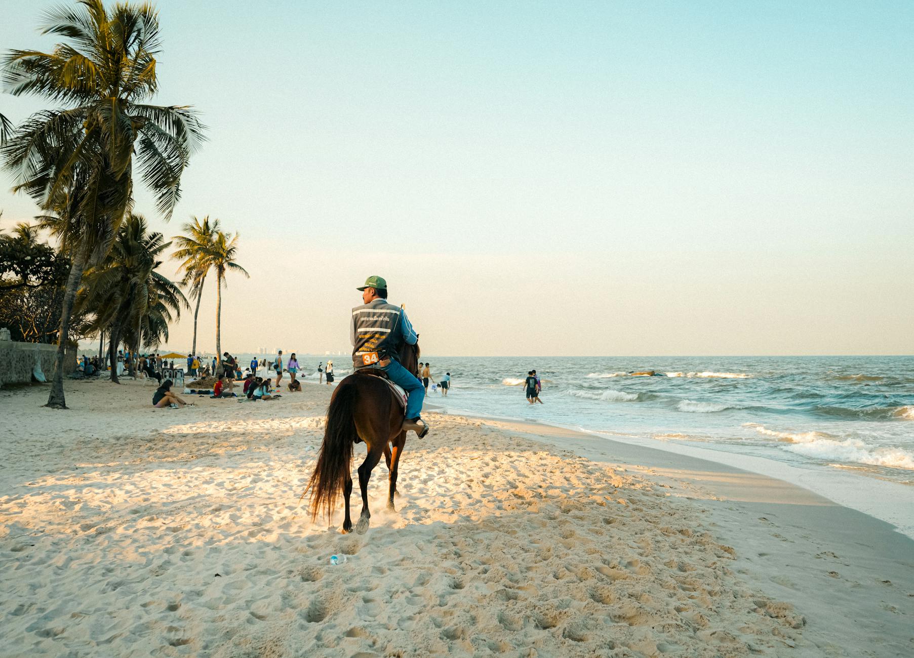 Jazda konna po słonecznej plaży w Tajlandii z palmami i turystami