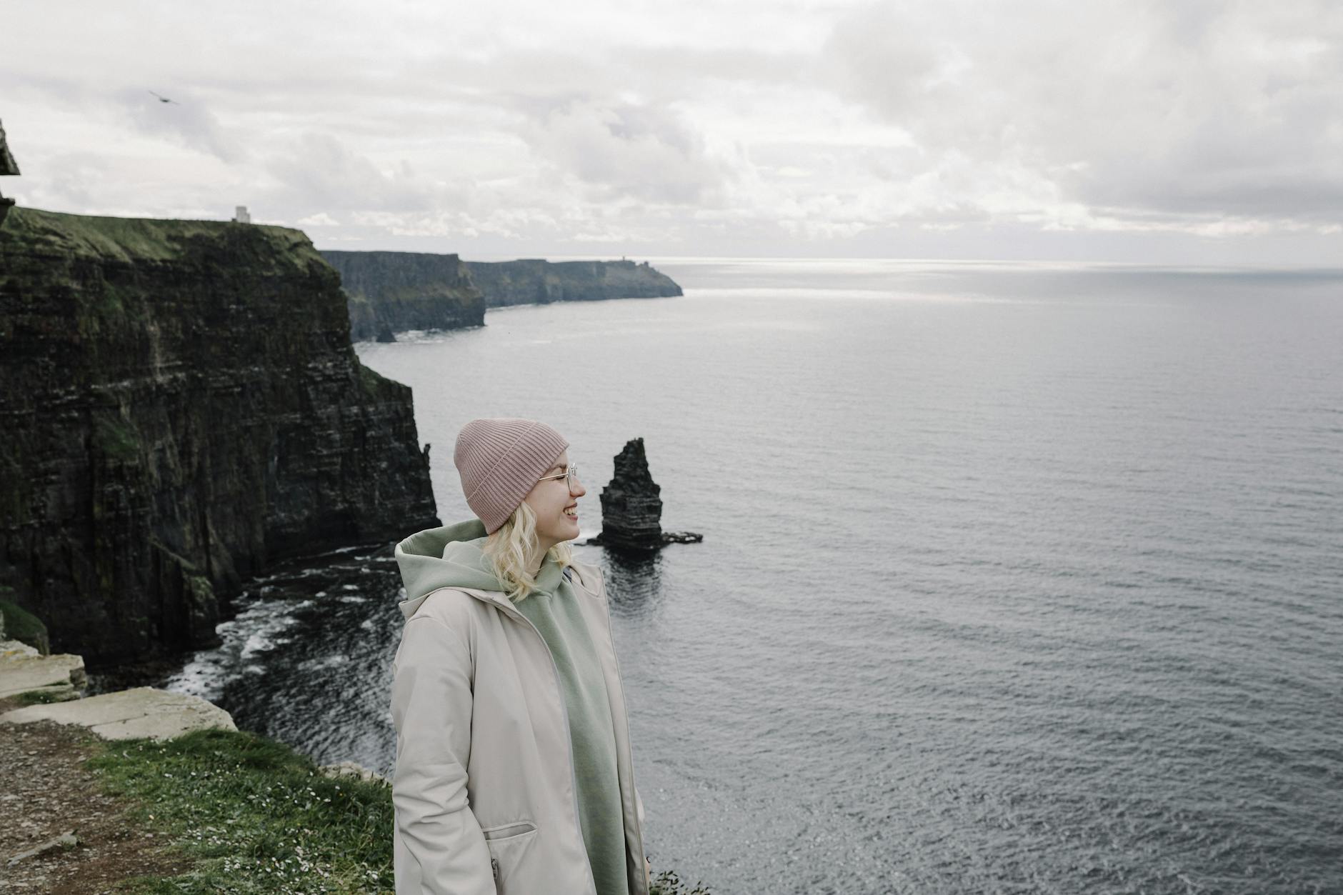 Kobieta uśmiecha się na tle Klifów Moheru nad oceanem