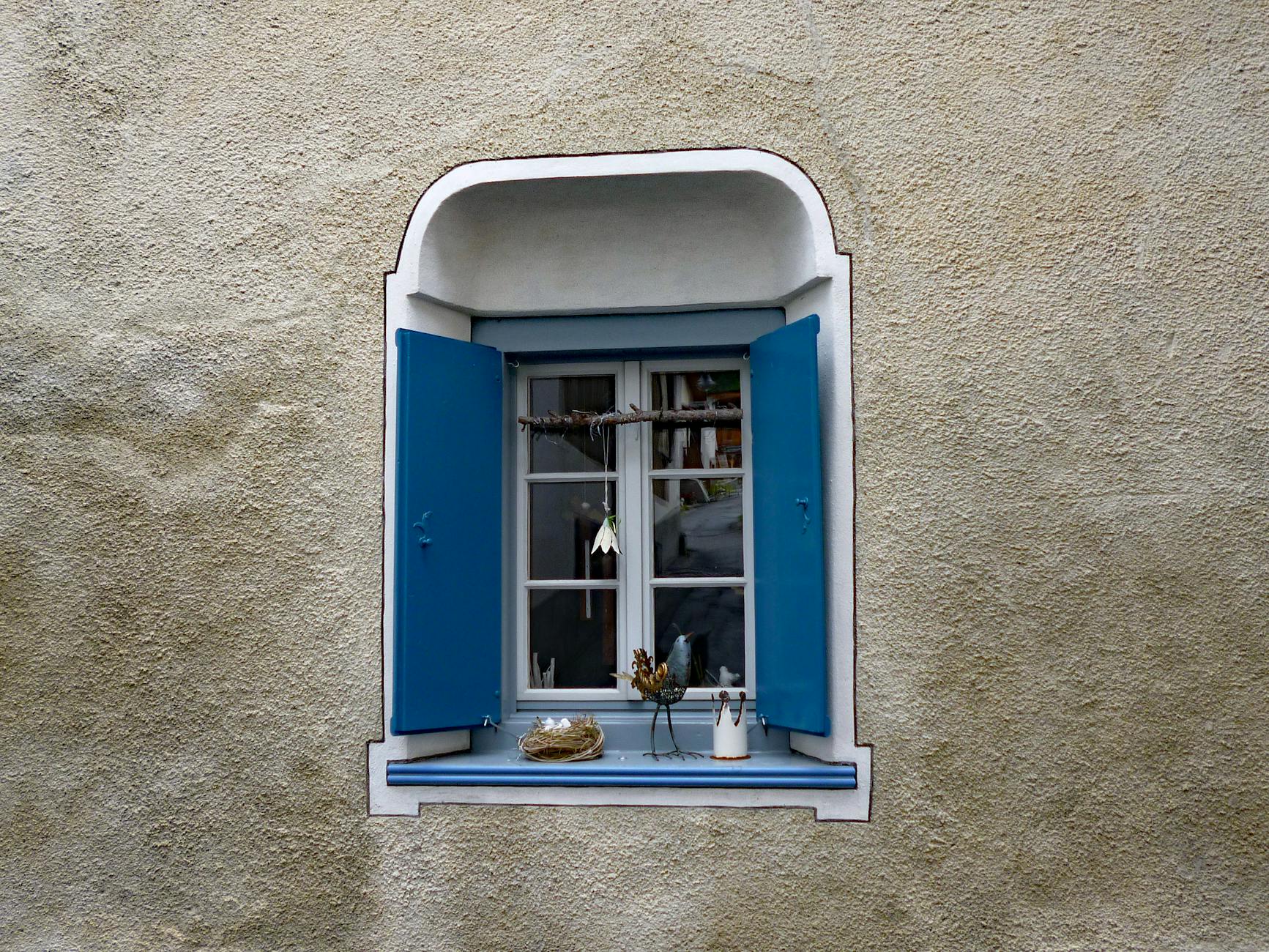 Niebieskie okiennice przy oknie w kamiennym tynku domu w Davos