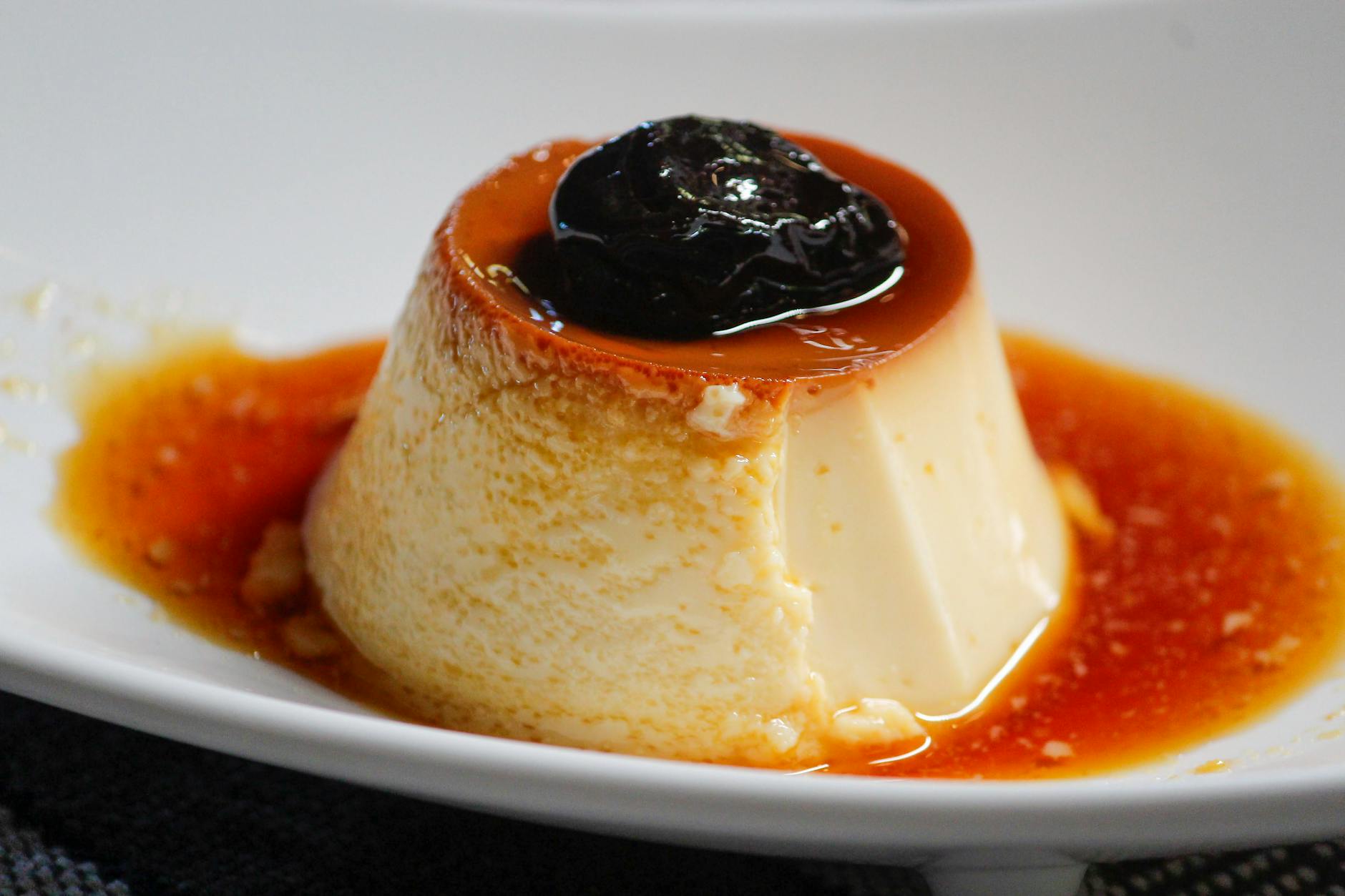 Flan z sosem karmelowym i suszoną śliwką na białym talerzu