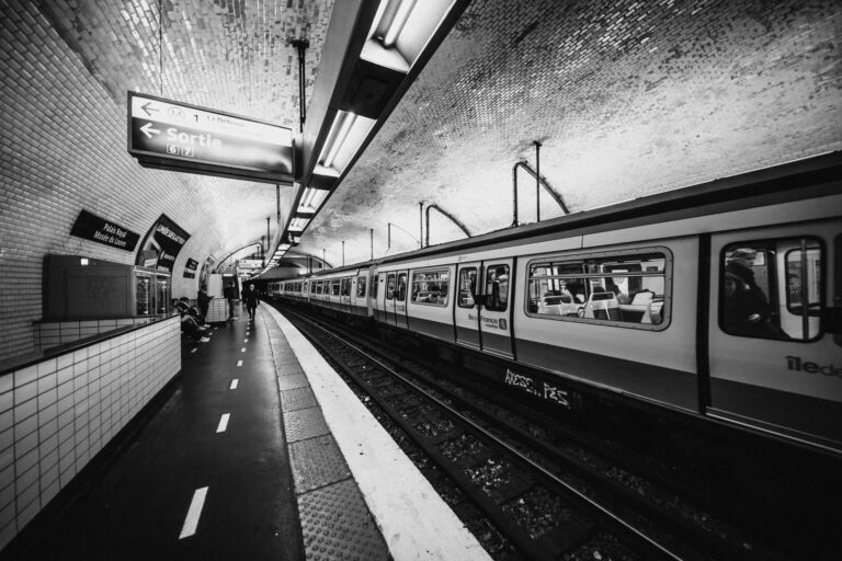 Czarno-białe ujęcie stacji metra w Paryżu z miejskim ruchem